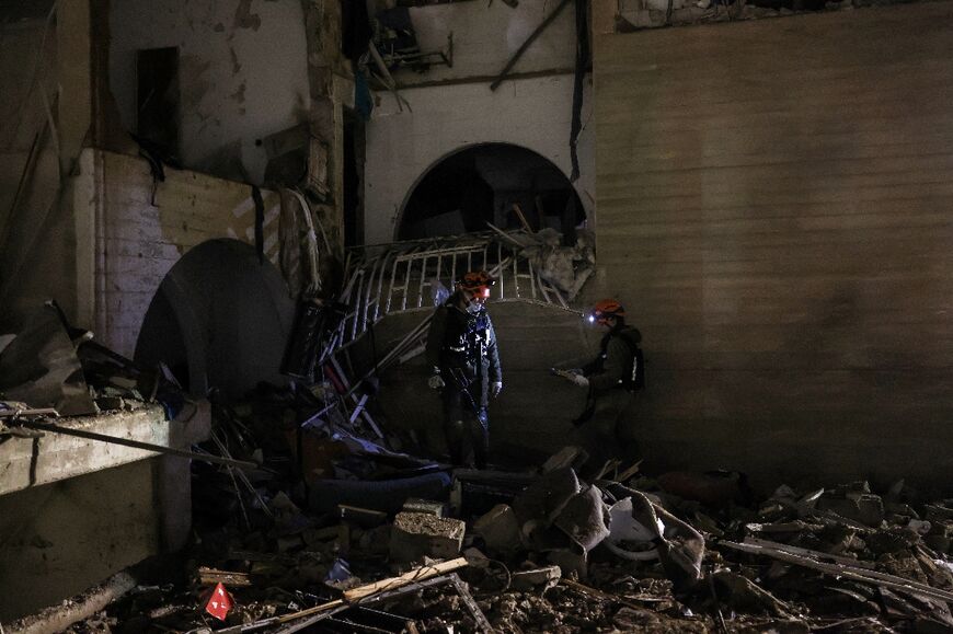 First responders inspect the site of an Iranian missile strike in Arad early on March 22, 2026