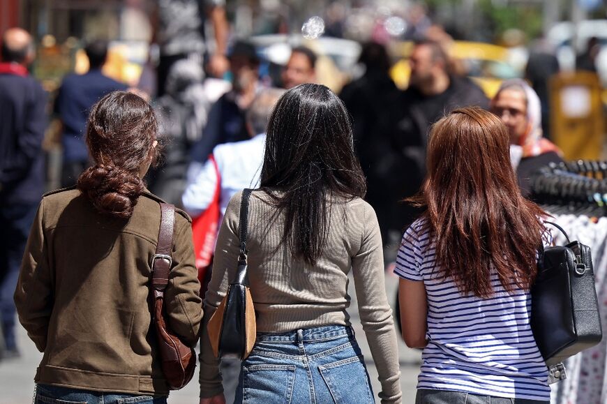 Iranian women walk along a busy street in Tehran