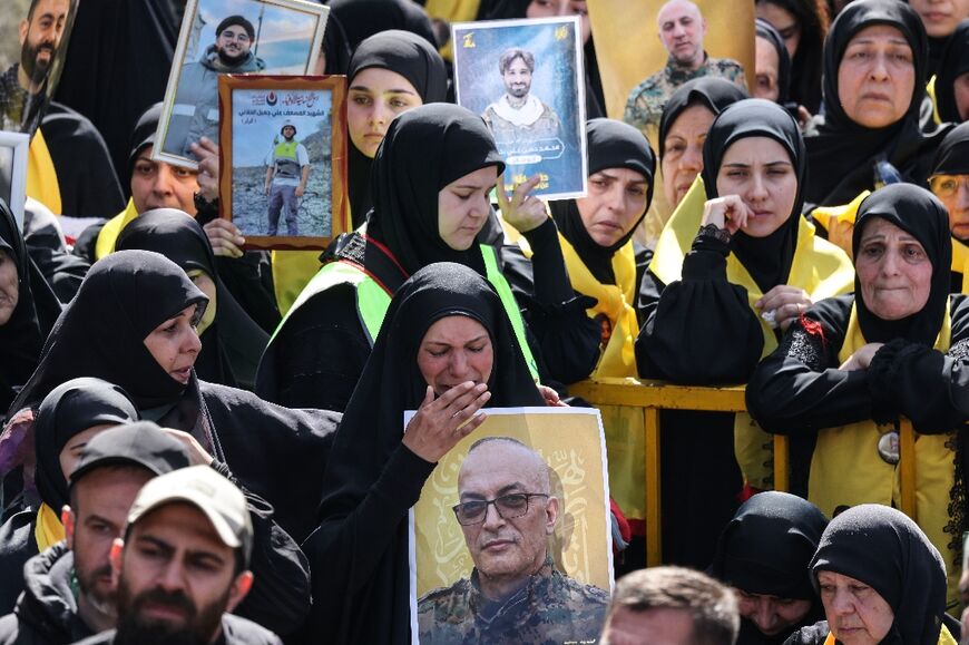 Mourners hold portraits of Hezbollah fighters killed before a 10-day ceasefire was agreed between the Iran-backed militant group and Israel during a mass funeral  in the southern village of Kfar Sir
