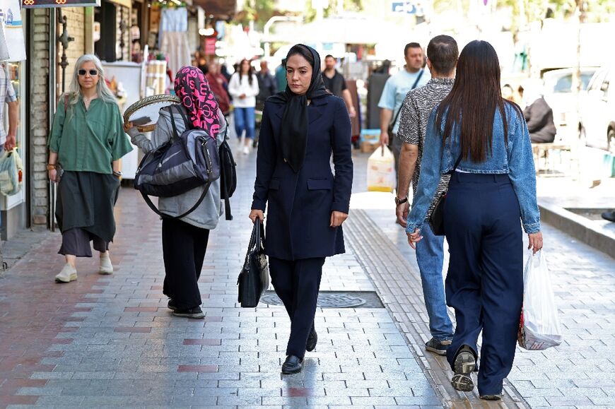 Iranian women walk along a busy street in Tehran