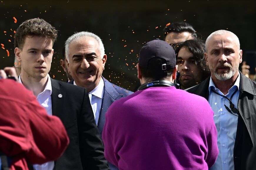 An activist, the second person from right, splashes a red liquid on the back of son of Iran's last shah, exiled Crown Prince Reza Pahlavi, after a Berlin press conference