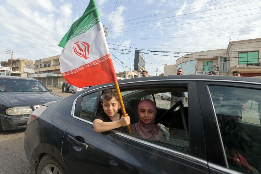 A boy holds an Iranian flag as he returns back to the southern Lebanese town of Marwanieh