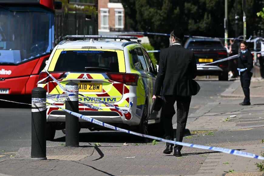People stand by a police cordon in Golders Green, north London after two Jewish men were stabbed, and a suspect arrested