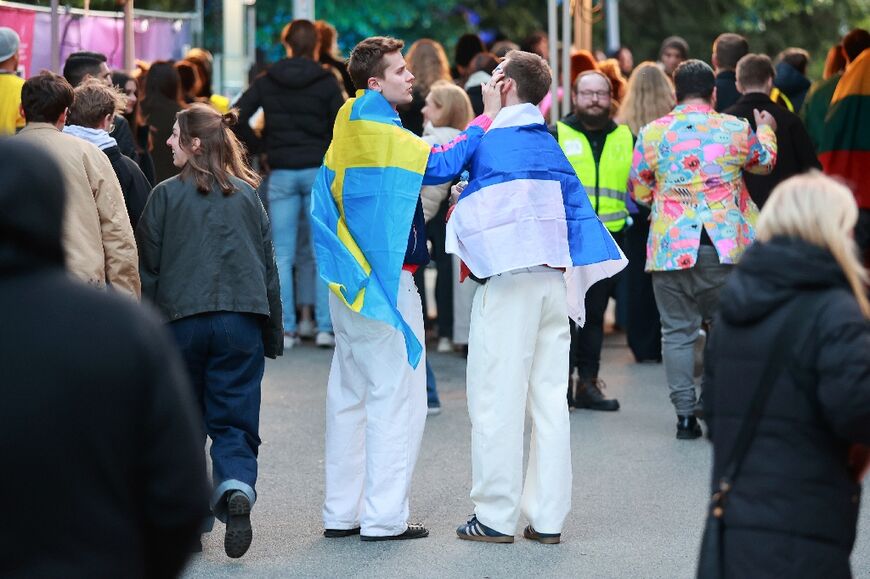 Eurovision fans draped in Swedish and Finnish flags arrive at the Wiener Stadthalle 