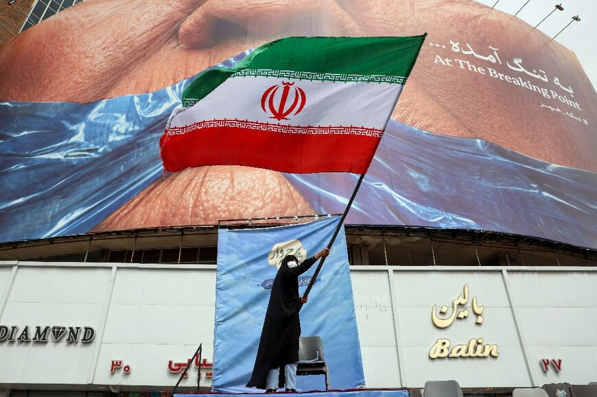 A woman waves an Iranian flag in front of an anti-US billboard referring at Valiasr Square in Tehran