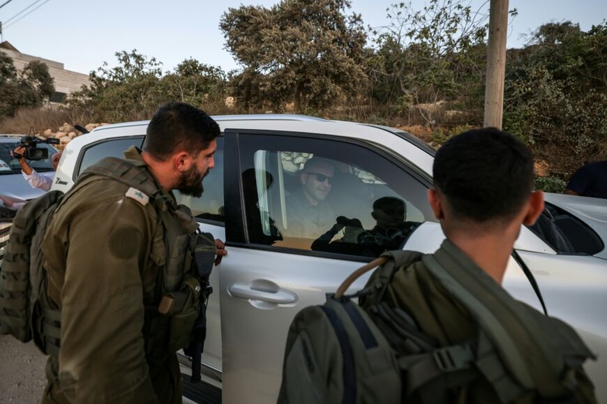 Israeli soldiers watch as US-Palestinian dual citizen Louai Abu Ridi, whose home in the Israeli-occupied West Bank village of Qusra is besieged by Israeli settlers, arrives by car to visit his mother at her home in the same village