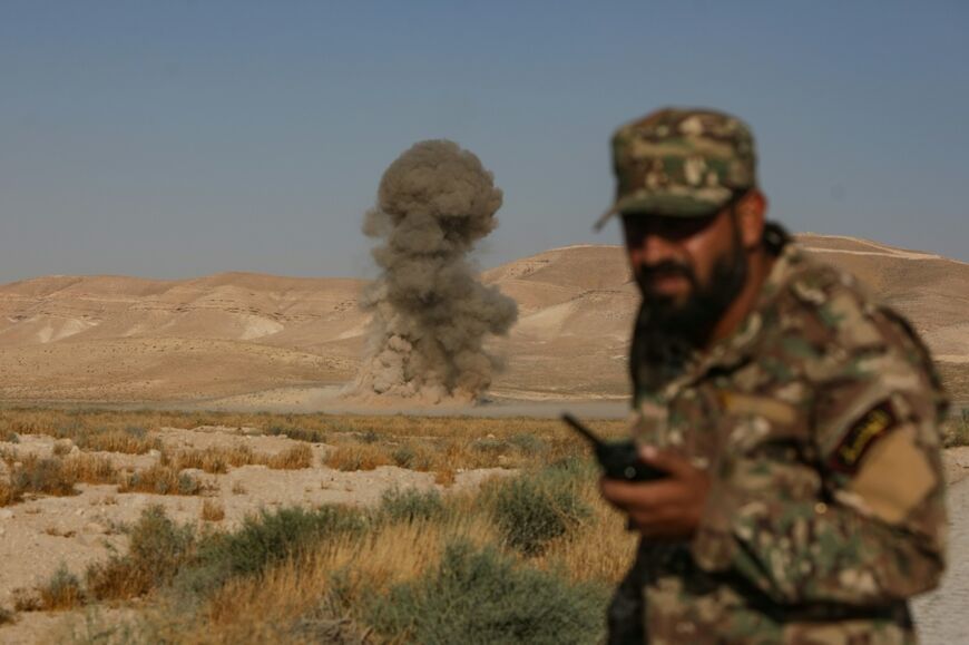 A Syrian army soldier ducks as a land mine explodes during a demining operation in Qarah in the Damascus countryside