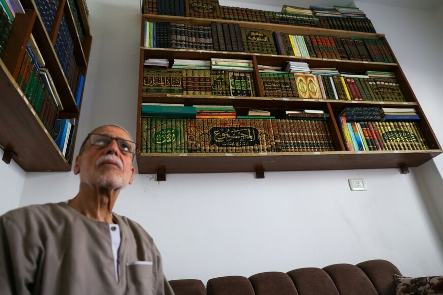 Mustafa Khaled Alwan poses for a picture surrounded by his books, which he retrieved after hiding them behind a false wall after the start of the uprising against longtime Syrian ruler Bashar al-Assad