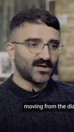 Iraqi Christian man in dark blue sweater sitting in an office 