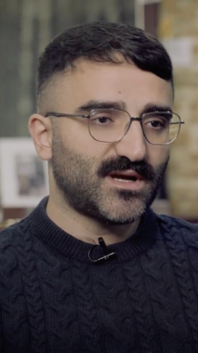 Iraqi Christian man in dark blue sweater sitting in an office 